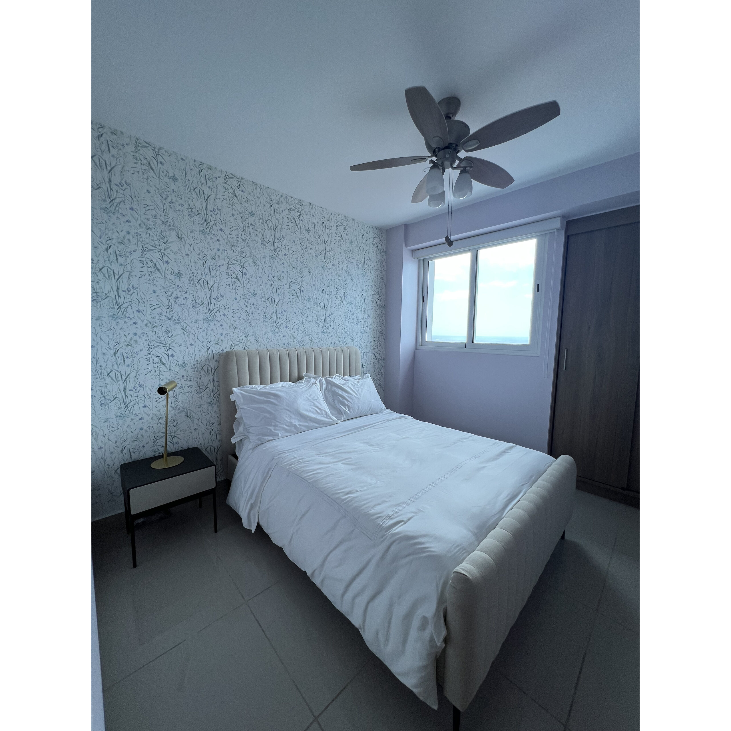 Recámara con cama individual, buró, clóset, ventana y ventilador de techo.