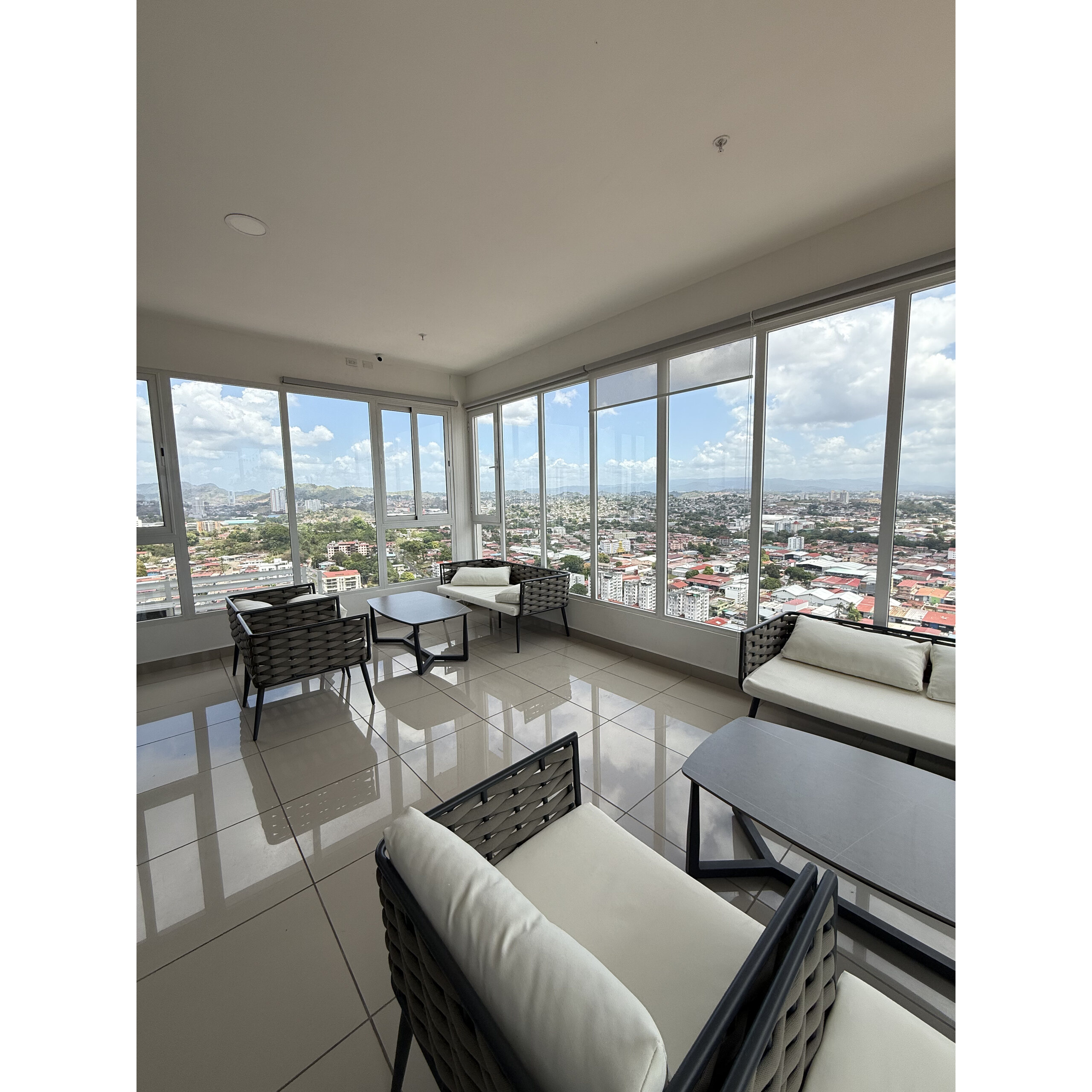 Área social interior con sillones y amplios ventanales con vista a la ciudad.