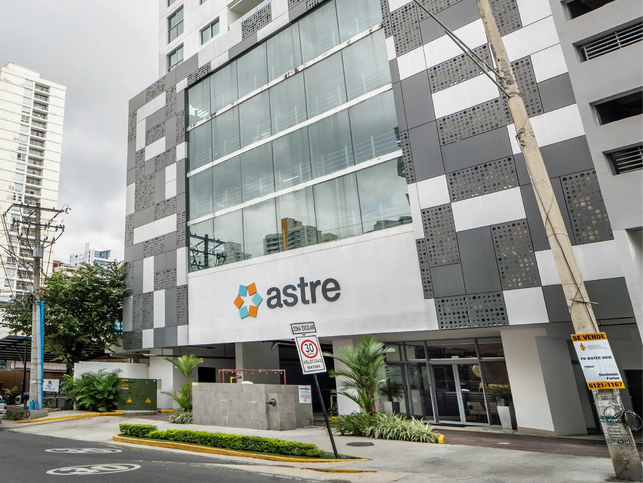Fachada del edificio Astre con paneles grises y blancos y grandes ventanales.