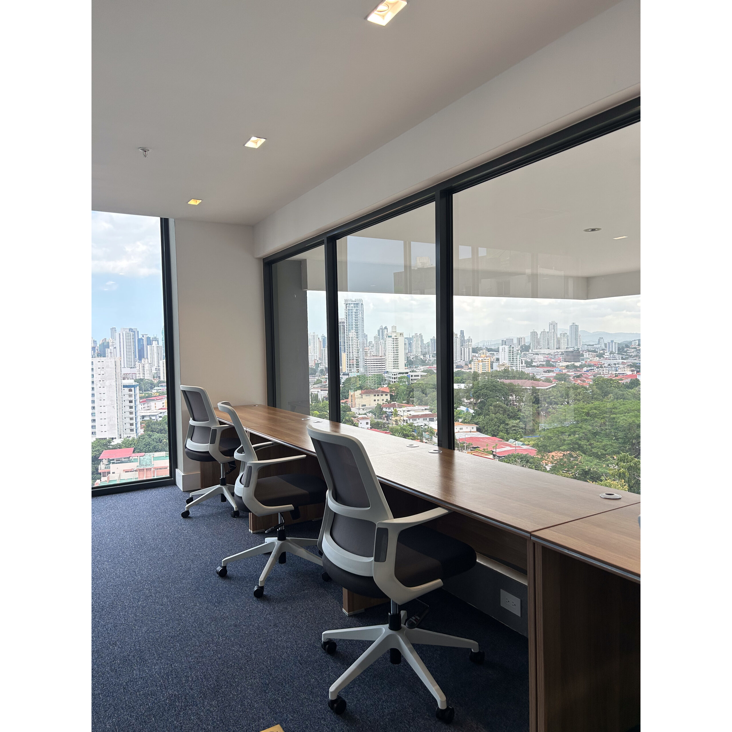 Área de coworking con escritorios y sillas junto a ventanales.