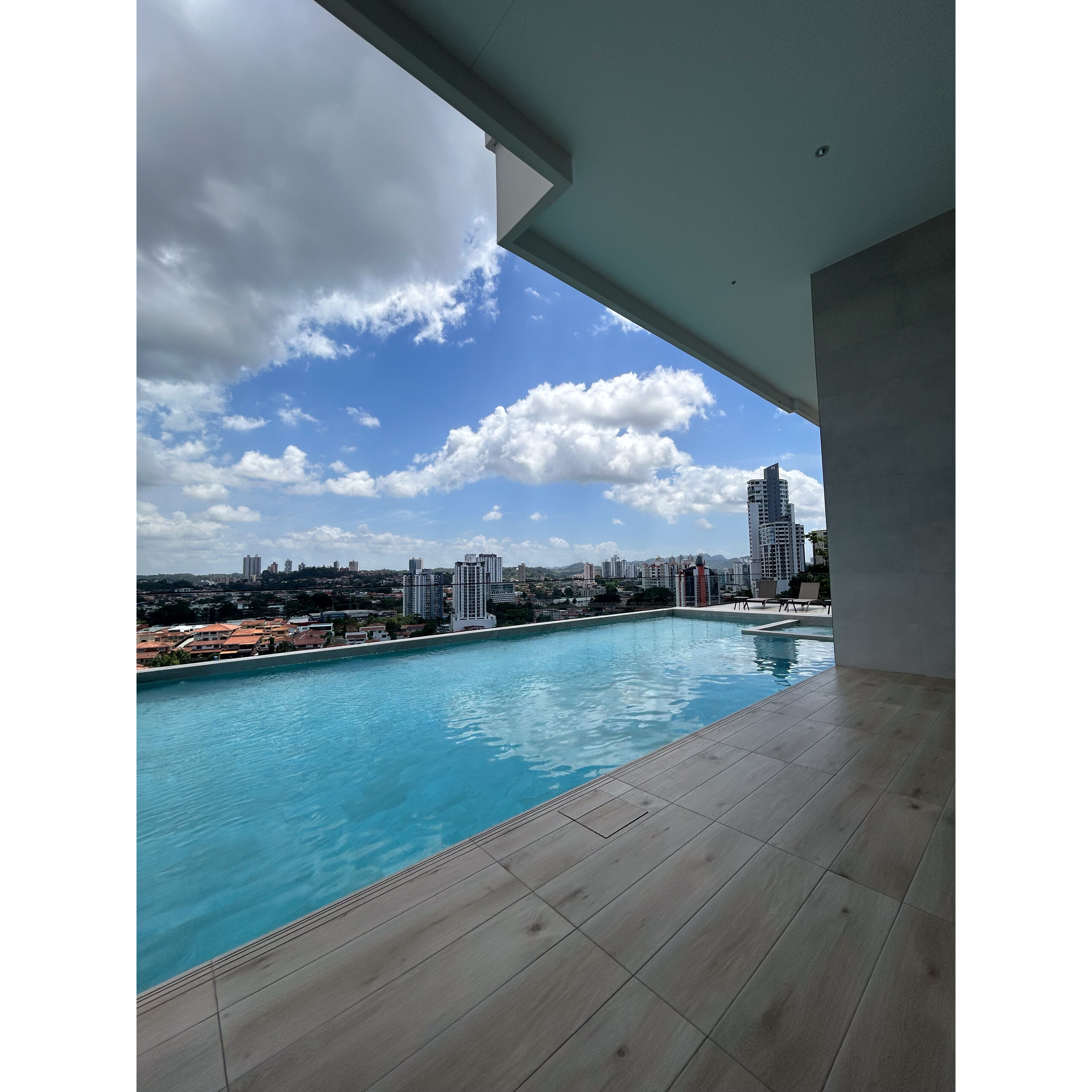 Piscina exterior con borde infinito y vista a la ciudad bajo techo moderno.