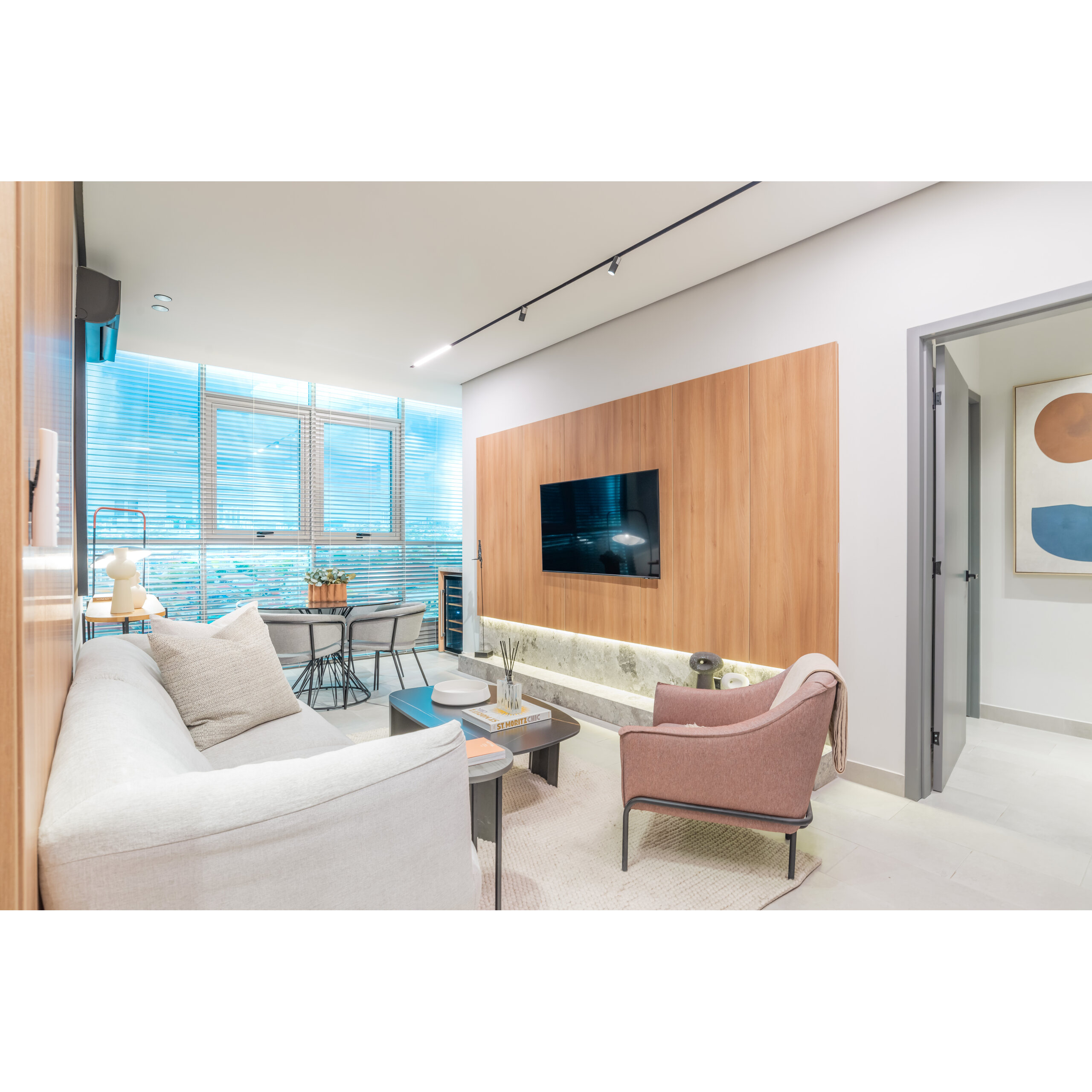 Sala moderna con sofá, sillón, mesa de centro y televisor en pared de madera.
