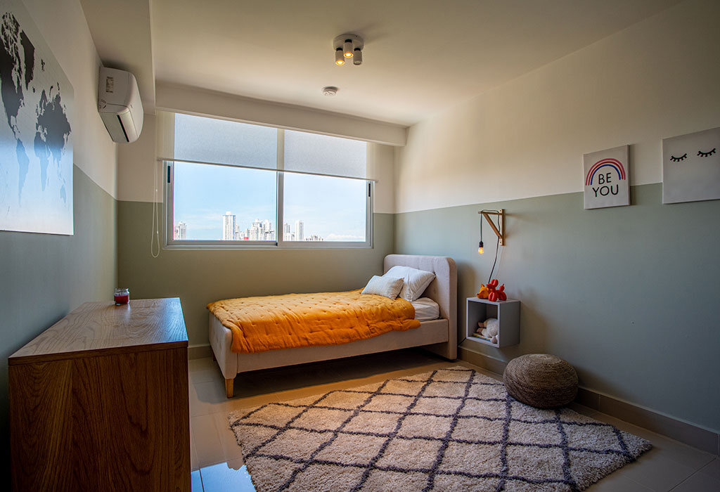 Recámara moderna con cama individual, ventana amplia y alfombra geométrica.