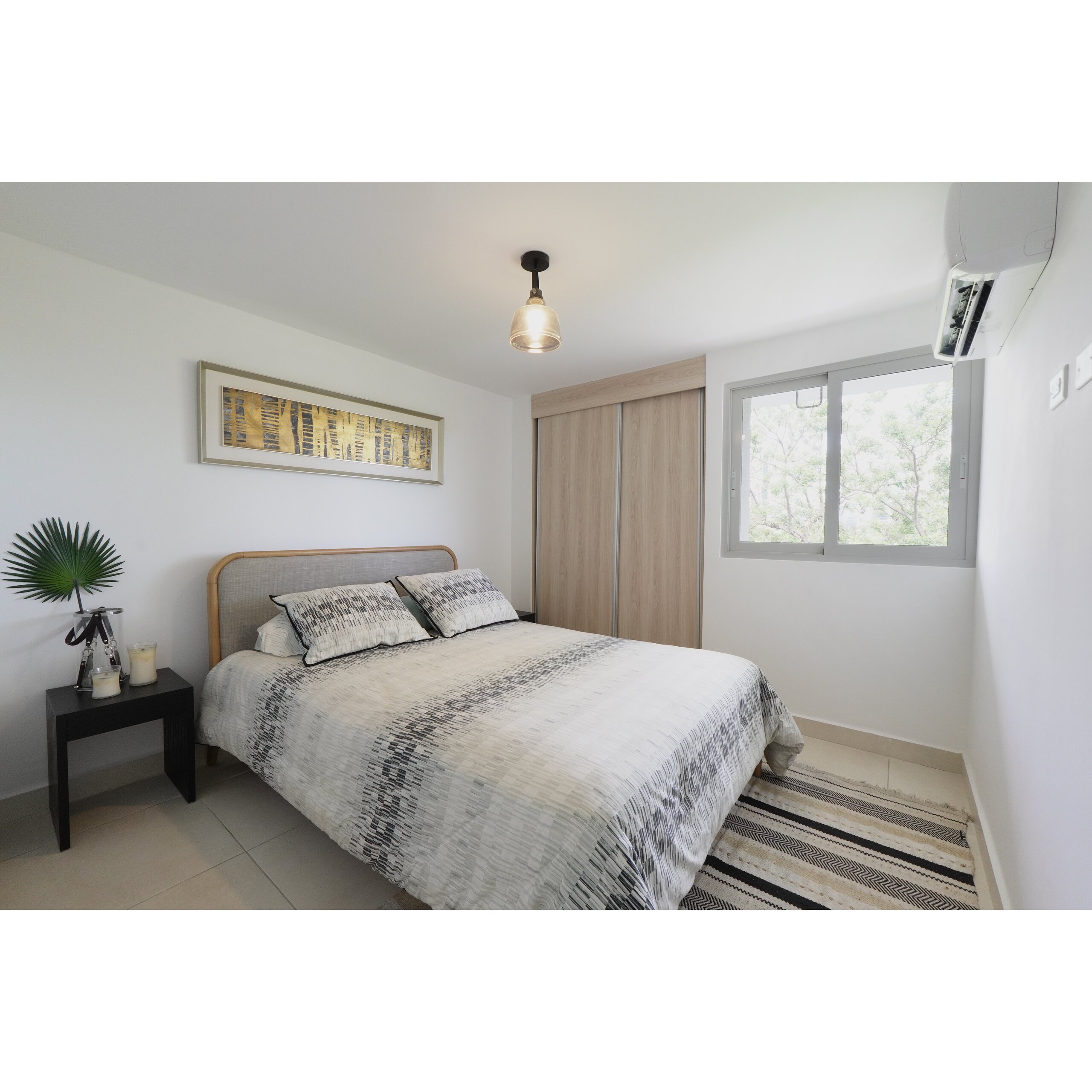 Recámara luminosa con cama doble, clóset de madera y ventana lateral.