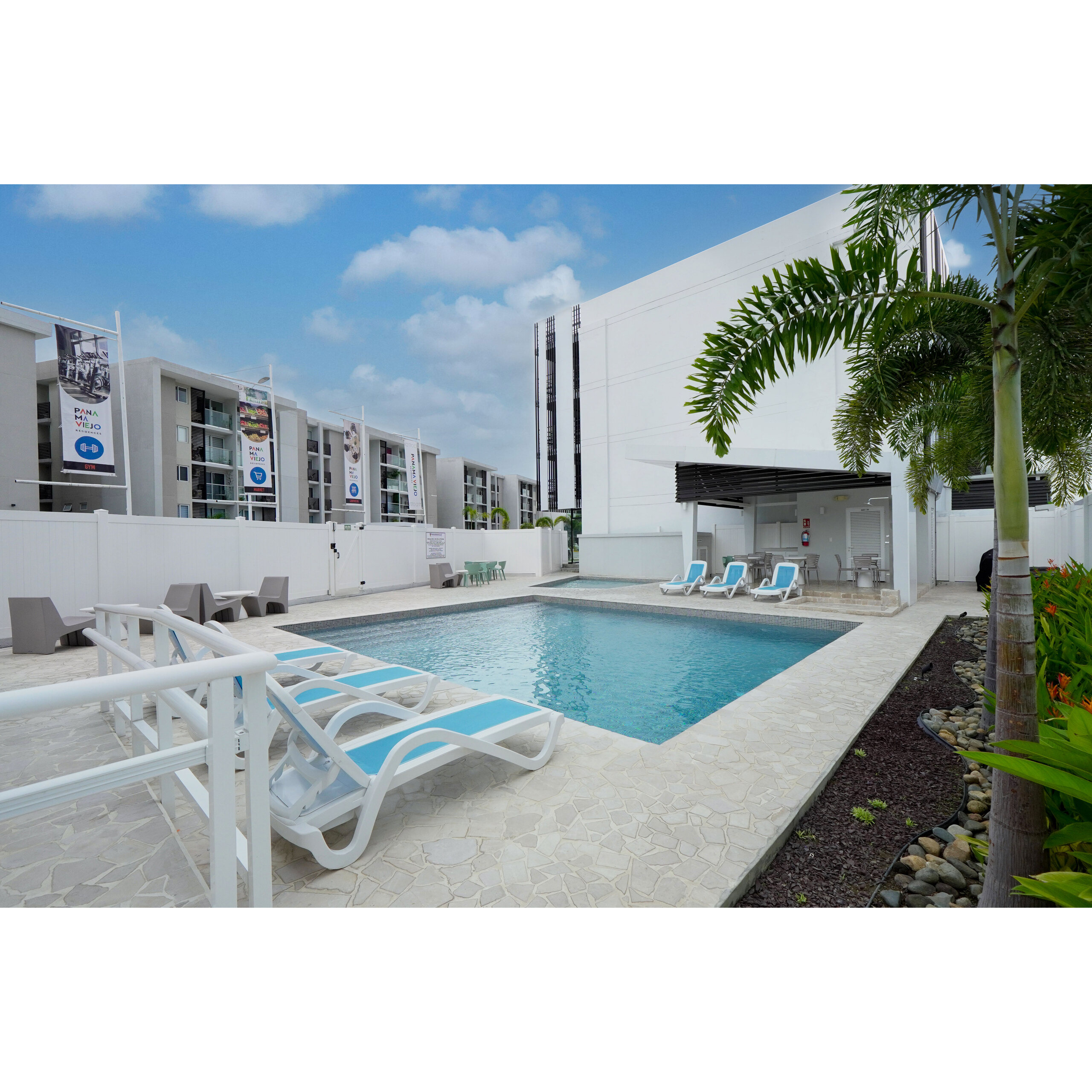 Piscina exterior de Panamá Viejo Residences con camastros y palmeras.