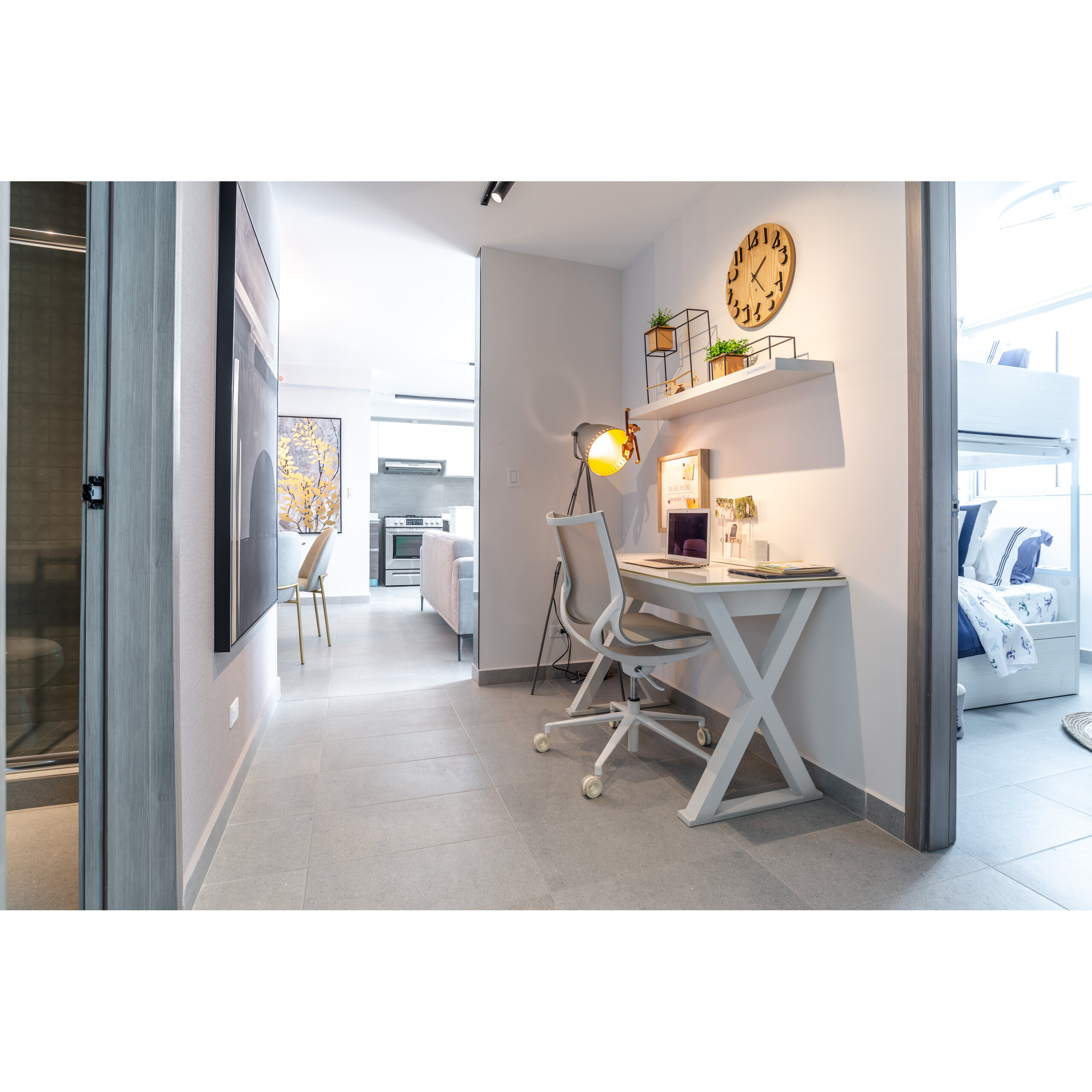 Área de estudio con escritorio, lámpara, silla y acceso a recámara y cocina.